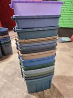 Stack of 13 assorted color Rubbermaid bins without lids