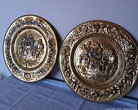Two Peerage brass wall plaques side by side showing size and design.