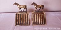 Front view of both brass horse bookends showing horse figures and book-spine bases