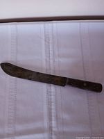 Overall view of vintage carbon steel slicer knife showing blade patina and wooden handle