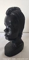 Front angled view of ebony female bust showing facial details and base