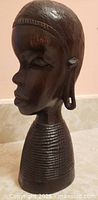 Front angle of carved Masai woman bust showing facial detail and neck rings