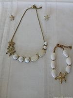 Necklace, bracelet and earrings laid flat showing design and size