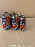 Front view of six commemorative Blue Light cans with Blue Jays graphics and plastic ring visible
