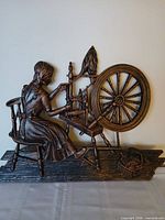 Front view showing detailed copper-finish relief of girl at spinning wheel