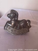 left-angle view of silver-plated rocking horse coin bank