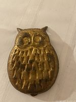 Front view of brass owl dish showing textured feather design