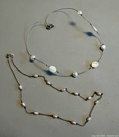 Both necklaces laid flat showing design and spacing of pearls