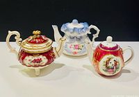 Front view of all three miniature teapots