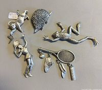 All five JJ pewter brooches laid flat showing fronts and scale tag