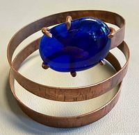 Angled view showing copper triple-band cuff and blue cabochon