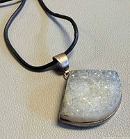 Front view of white druzy quartz sterling pendant on black cord