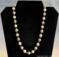 Full view of necklace on display bust showing alternating pearl pattern