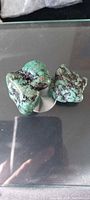 Two green dyed howlite stones on reflective surface