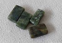 Four polished green serpentine rectangles on fabric background