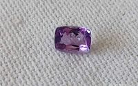 Front view of rectangular cushion-cut amethyst on fabric