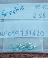 Group of 18 small faceted green sapphires in packet labeled with weight