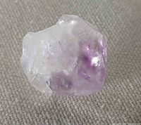 Amethyst crystal point on fabric background showing color and termination