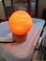 Lamp illuminated showing spherical salt crystal on wood base