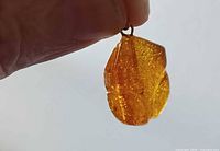 Front view of amber pendant held by hand