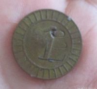 obverse side of brass token showing Arabic numeral 1 and grooved border