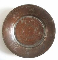 Front view of round copper-tone etched plate