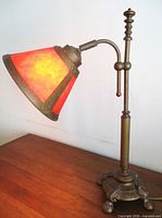 Full view of bronzed table lamp on wooden surface
