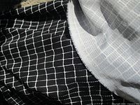 Close-up of black fabric with white grid pattern showing texture and selvage