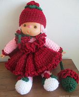 Full view of Strawberry Shortcake doll seated showing dress, hat and legs