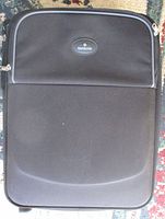 Front view of black Samsonite soft-sided suitcase showing logo and front zip pocket