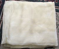 Folded rubber mesh pad on patterned rug