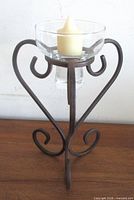 front view of wrought metal heart candle holder with glass cup and candle