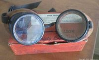 Willson Safety Cup goggles resting on original orange box, showing brand and lens condition