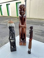 Group shot of all three carved wooden figurines showing relative sizes