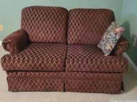Front view of burgundy diamond-pattern loveseat with pillow