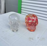 Two glass skull paperweights side-by-side, showing clear and flame versions