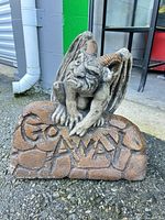 Front view of concrete gargoyle statue on rock reading Go Away