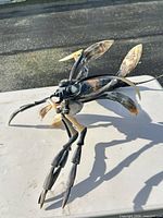 Full side view of cow horn insect sculpture showing legs and wings