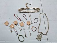 Overall view showing necklace, shell bracelet, four rosary bracelets on cards, three stretch bracelets and purple crystal bracelet