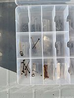 Open plastic organizer showing various barbells, rings and studs in separate compartments and bags