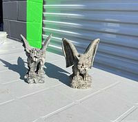 Both gray resin gargoyle statues side by side on table