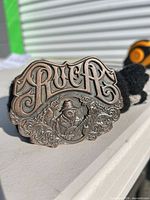 Front view showing RVCA lettering, ornate design, antique copper finish