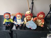 All four ceramic Raggedy dolls seated on table