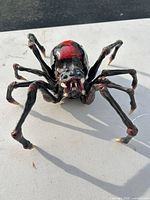 front view of spider figurine showing fangs, legs, paint detail