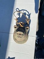 Front view showing sun face motif and rope hanger