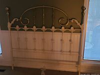 Full view of twin brass and white metal headboard against wall