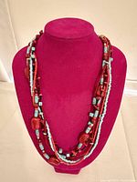 Full view of multi-strand turquoise and red beaded necklace on display bust