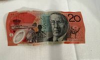 Front view of Australian $20 polymer note with John Flynn portrait, serial and security features visible, shows fold creases