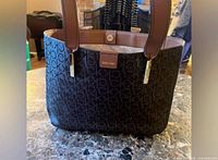 Front view of Calvin Klein brown monogram tote on marble surface