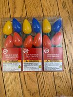 Front view showing three sealed packages of light-up LED bulb necklaces